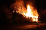 The fire is already burning hot before firefighters even get a hose on it. Notice the hose at the bottom of the screen./Photo by Lew Watters.